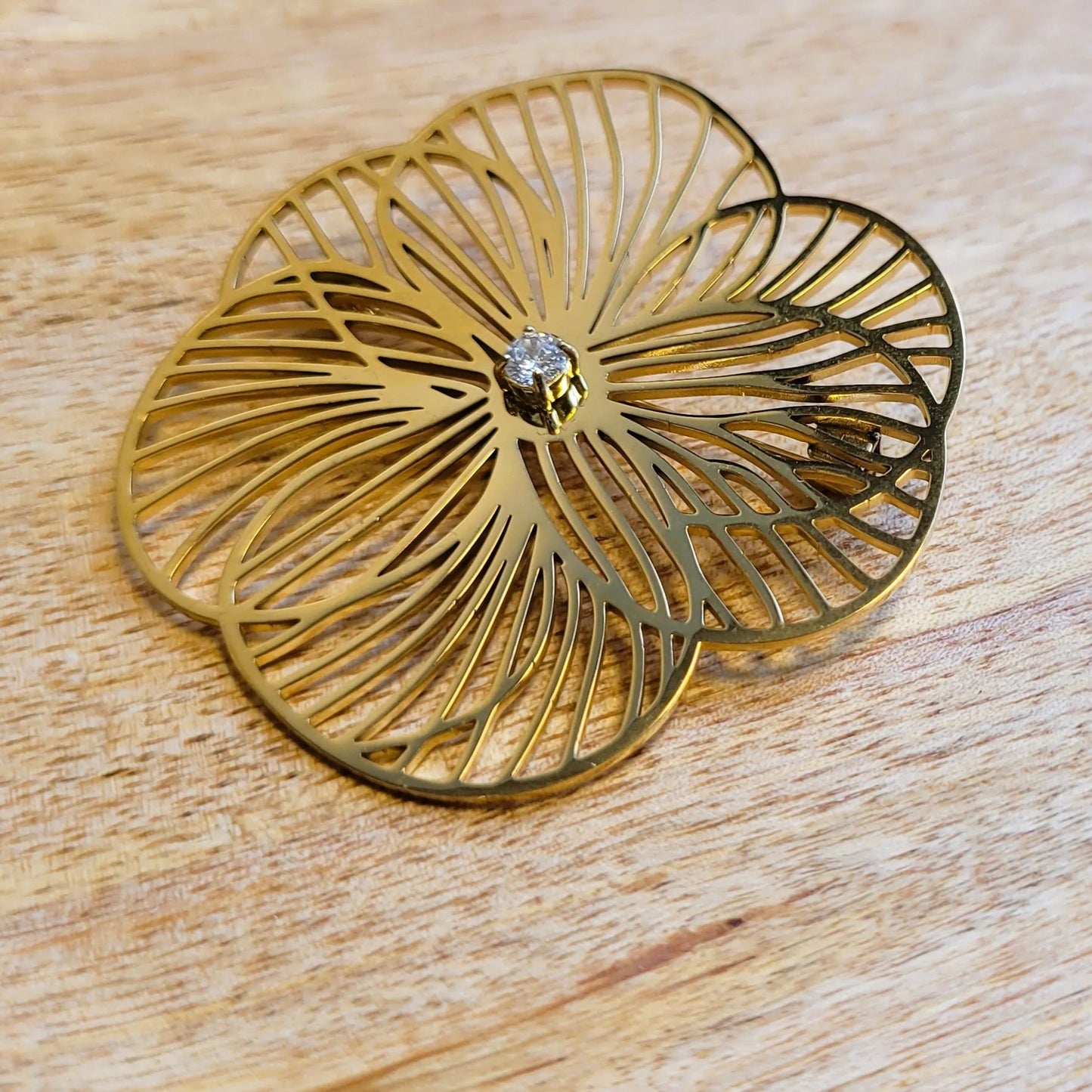 une broche dorée Camélia de luxe d’une fleur aux pétales ajourés