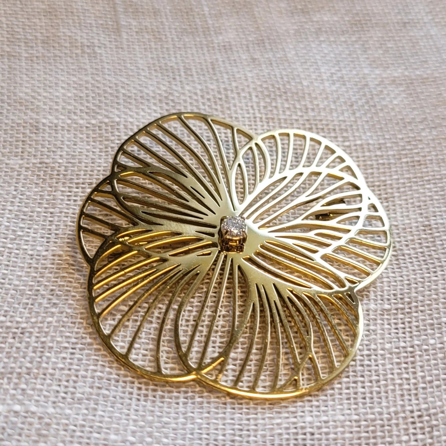 une broche dorée Camélia d’une fleur aux pétales ajourés pour sublimer un petit haut