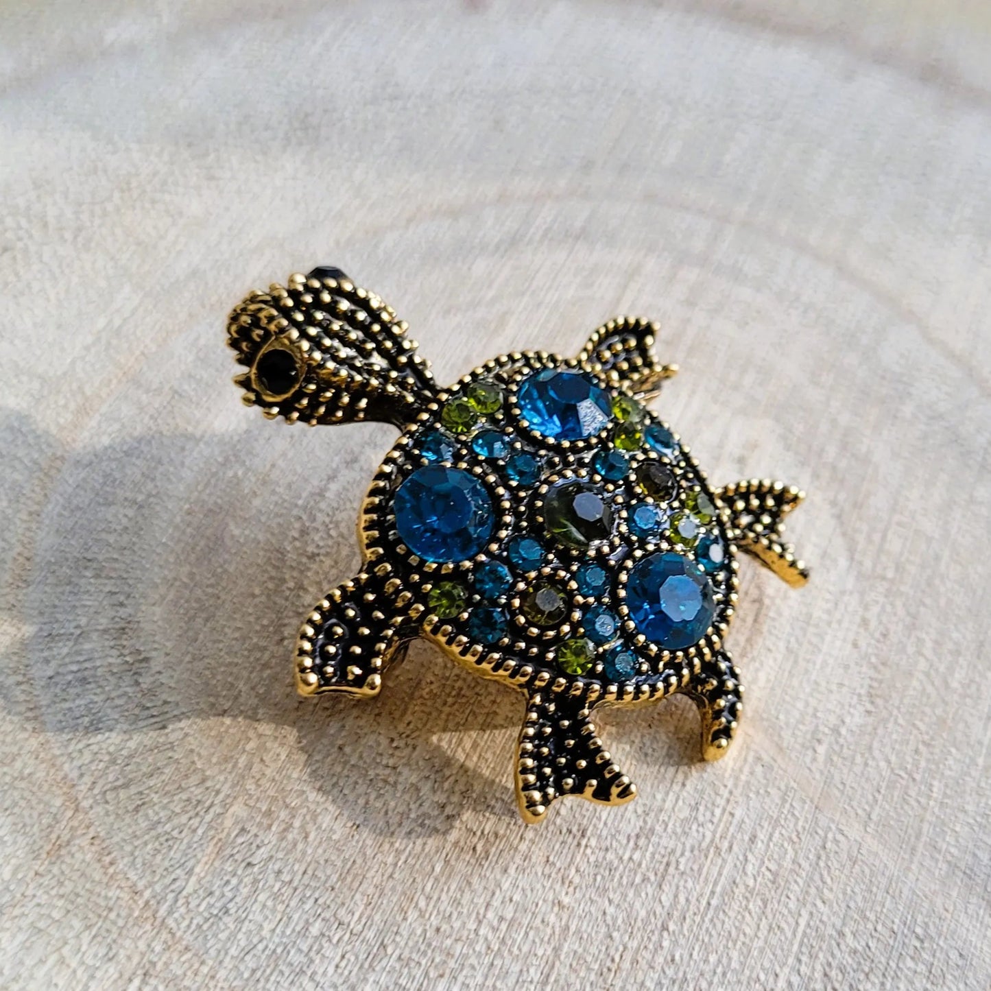 une broche dorée Caroline de luxe d’une tortue ornée de strass bleus et de picots