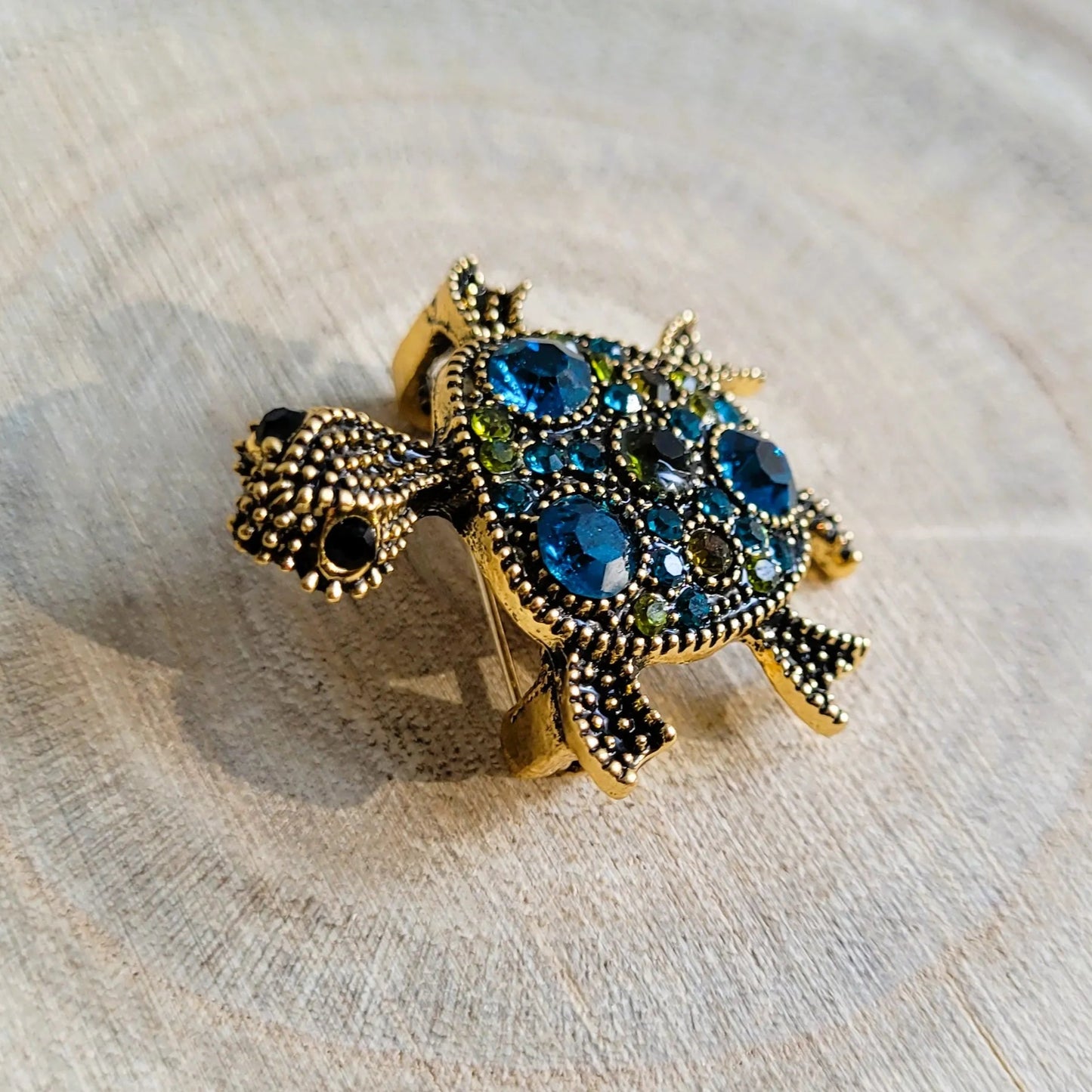 broche dorée Caroline d’une tortue ornée de strass bleus et de picots de la collection de broches bijoux