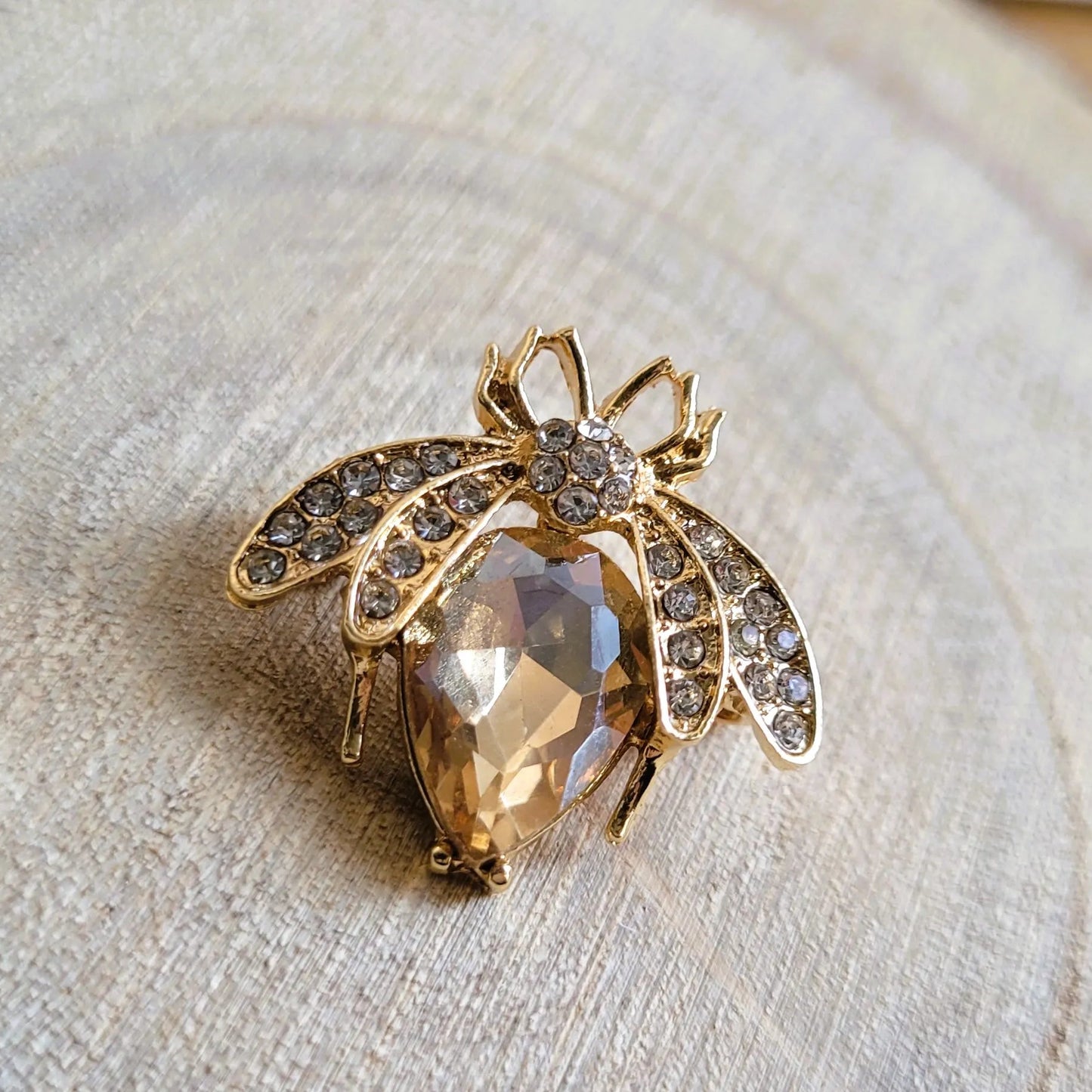 une broche dorée Mellya de luxe d’une abeille ornée d’un strass nude