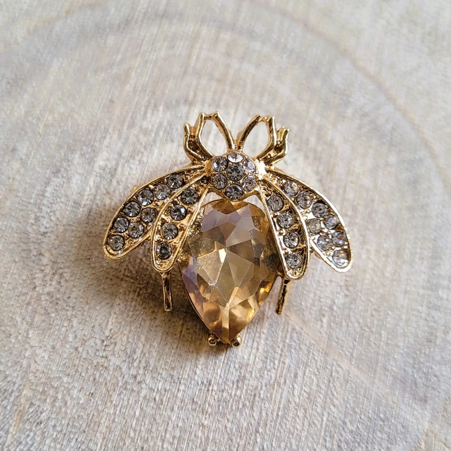 une broche dorée Mellya d’une abeille ornée d’un strass nude pour sublimer un petit haut