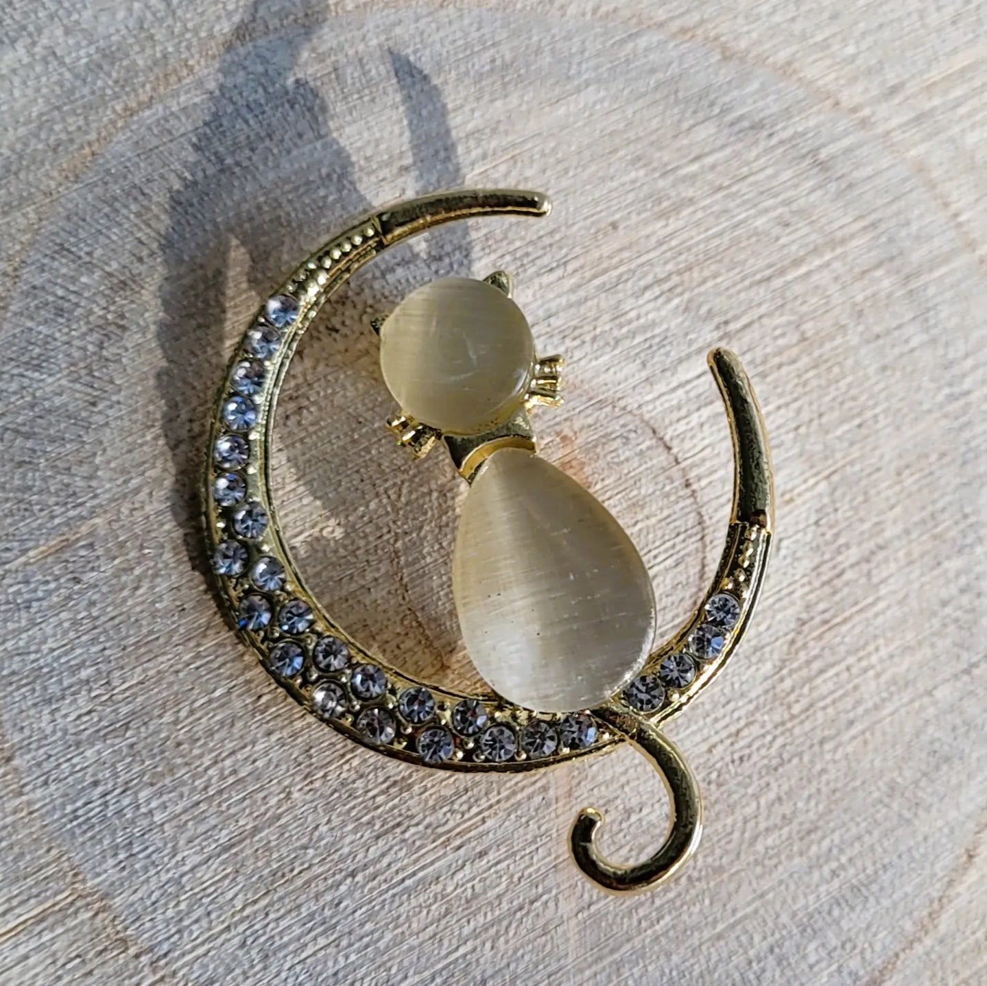 une broche dorée Mooncatz de luxe d’un chat rêveur sur un croissant de lune