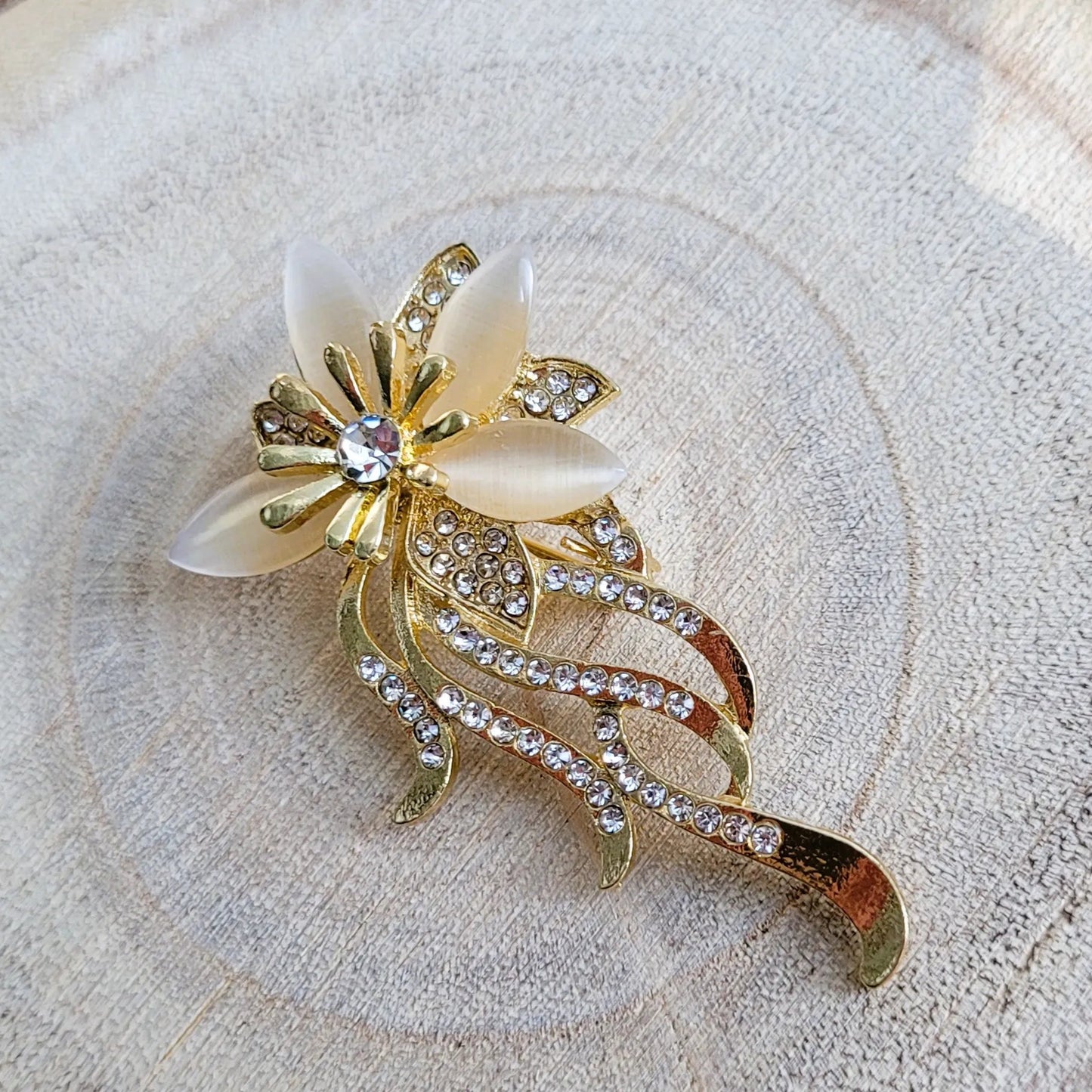 une broche dorée Orphéa de luxe d’une fleur aux délicates longues tiges