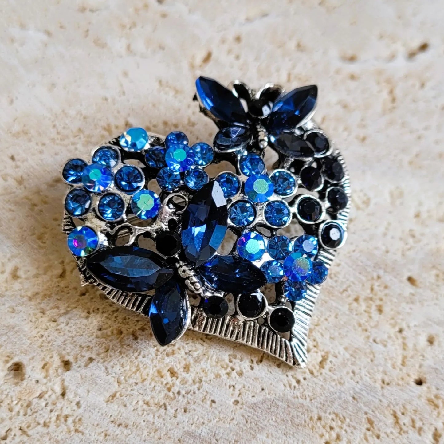 broche dorée Sentimientos, un bijou moderne d’un cœur de papillons et de strass bleus