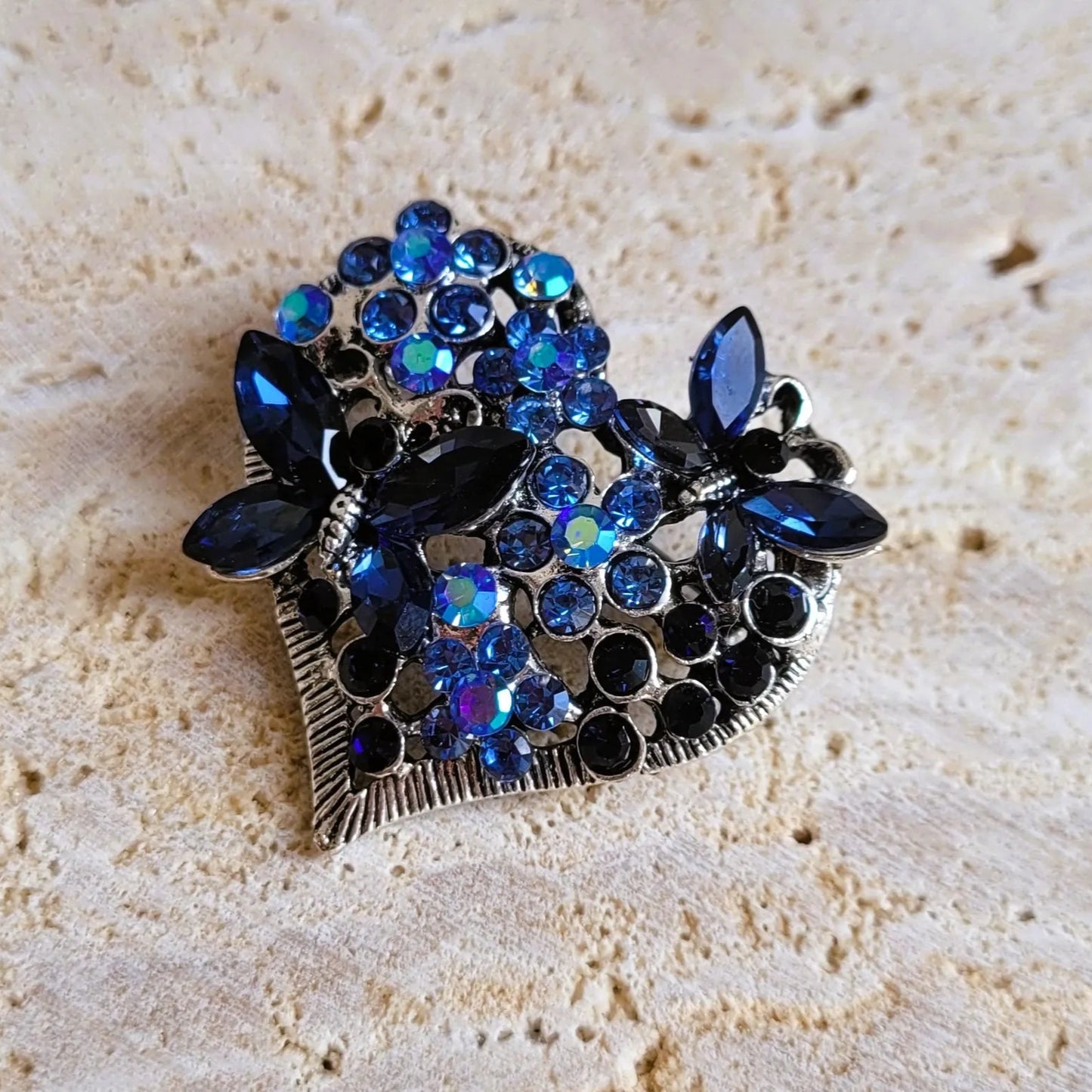 une broche dorée Sentimientos de luxe d’un cœur de papillons et de strass bleus