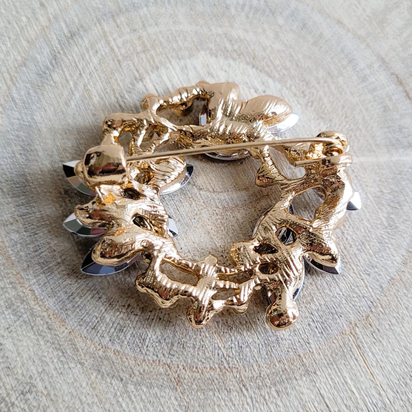 une broche dorée Sublim de luxe en couronne de strass bleus et cristal