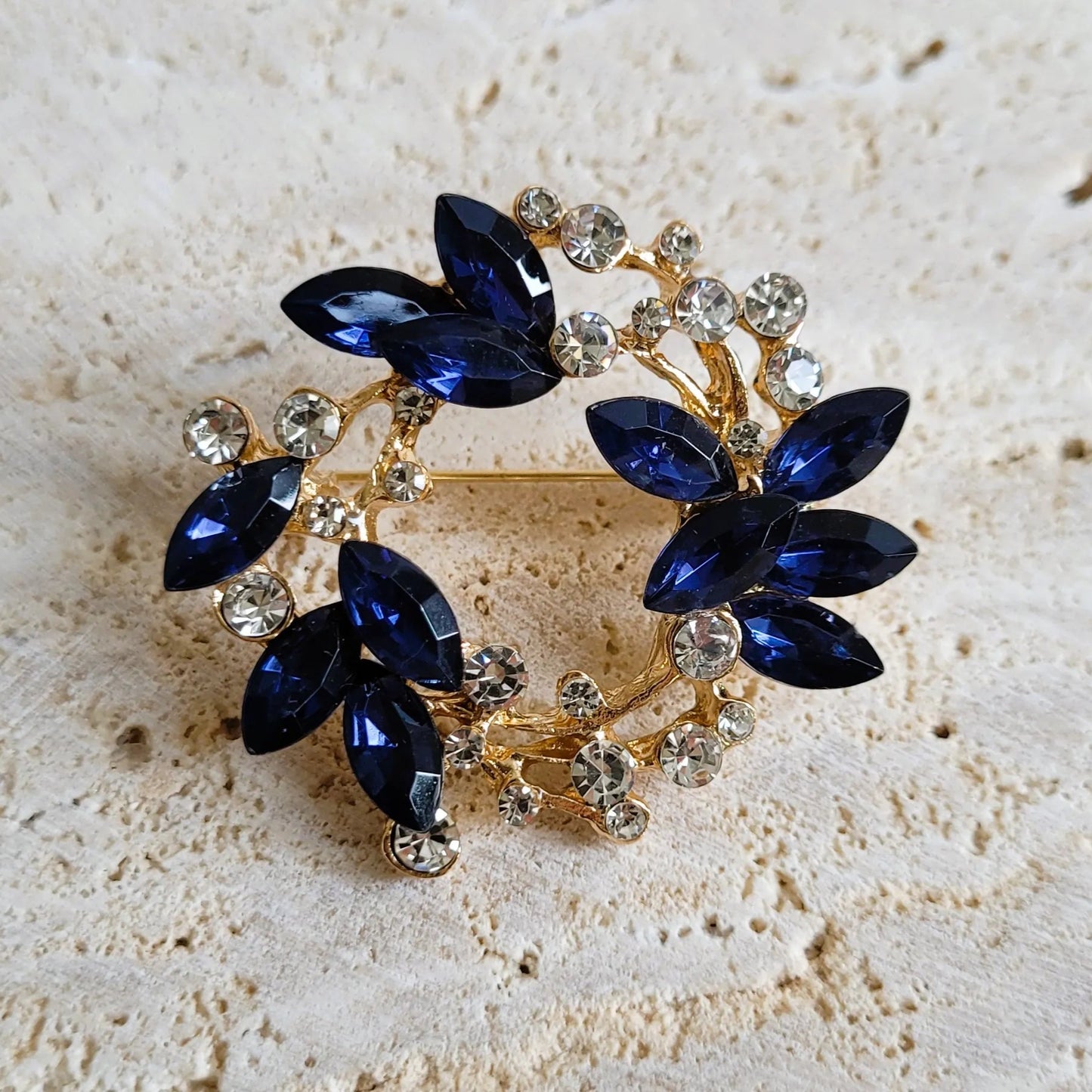 une broche dorée Sublim en couronne de strass bleus et cristal pour sublimer un petit haut