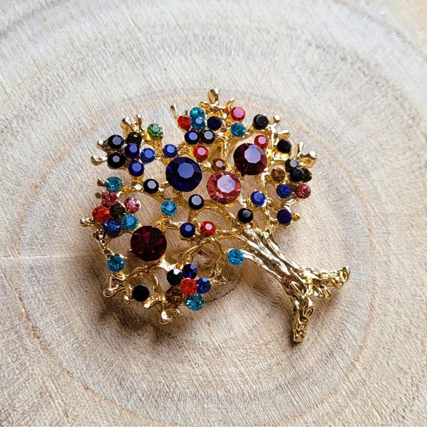 une broche dorée Via de luxe d’un arbre de vie aux strass multicolores