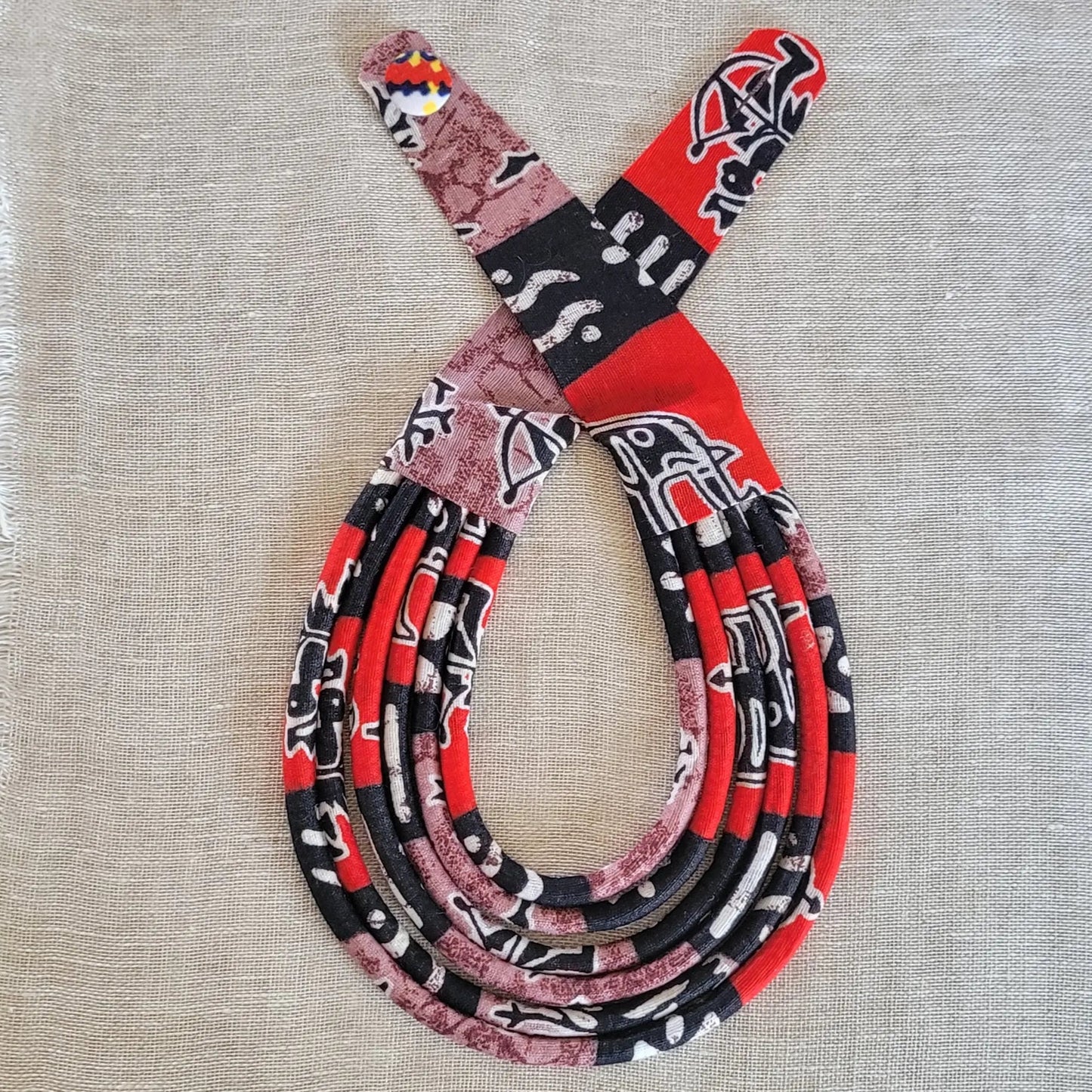 collier en tissu Aja, un bijou africain traditionnel en pagne noir, rouge et brun violet
