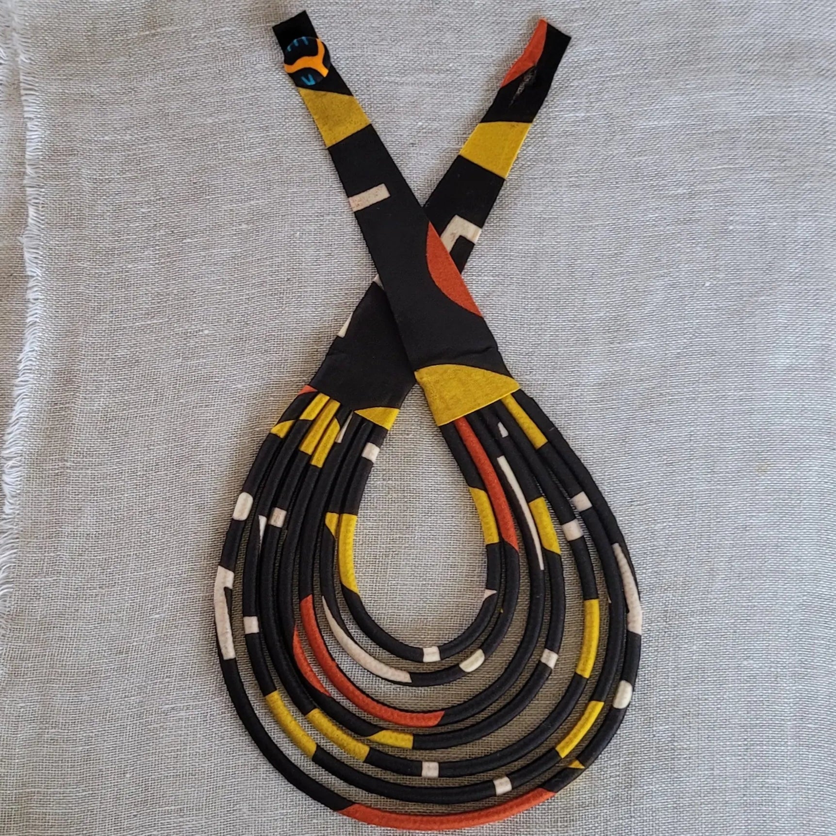 collier en tissu Diena, un bijou africain traditionnel en pagne noir, rouille et jaune moutarde