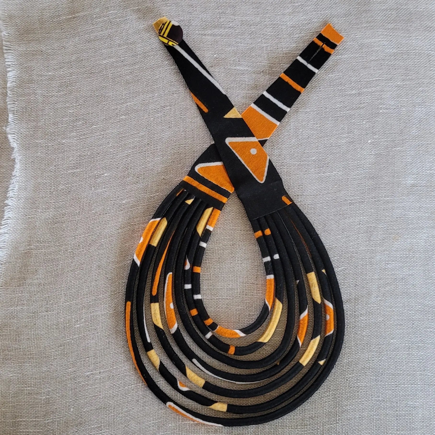 collier en tissu Fidèle, un bijou africain traditionnel en pagne noir et orangé