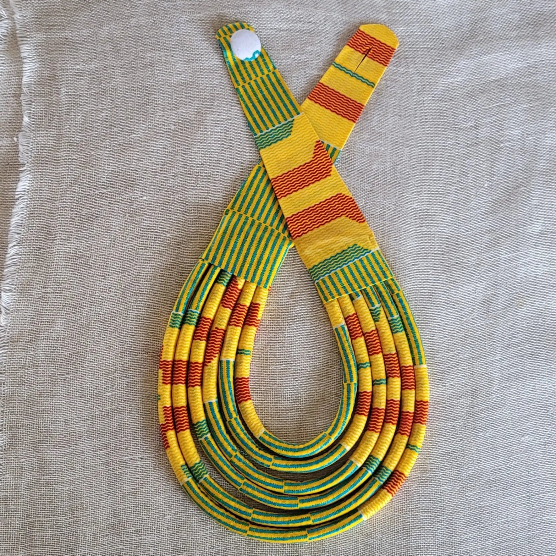 collier en tissu Malia, un bijou africain traditionnel en pagne jaune, rouille et turquoise