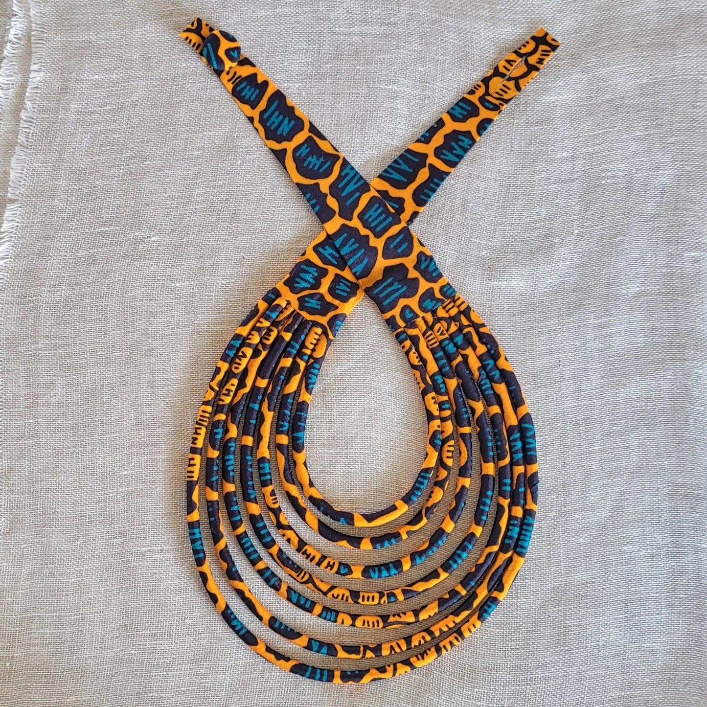 collier en tissu Nabintou, un bijou africain traditionnel en pagne orange, noir et bleu canard