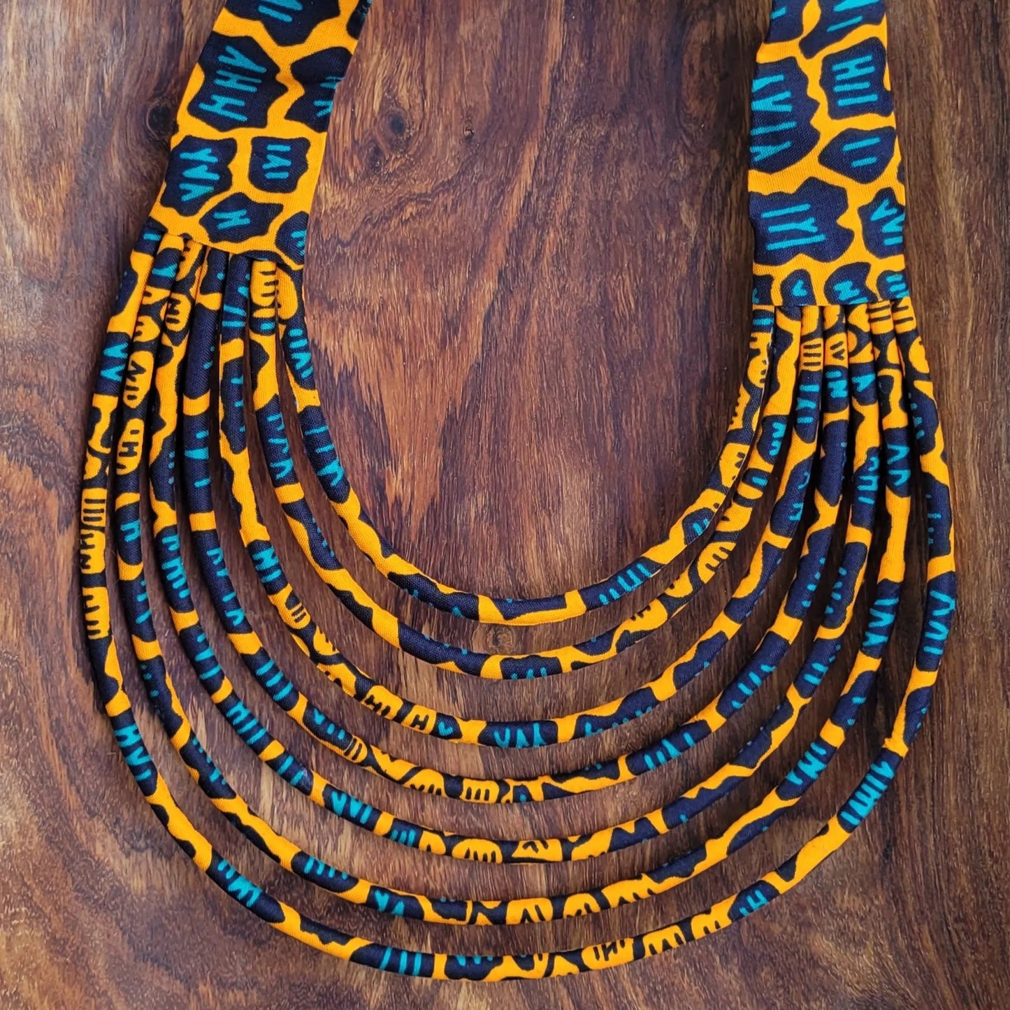 collier en tissu Nabintou, un collier coloré en pagne orange, noir et bleu canard