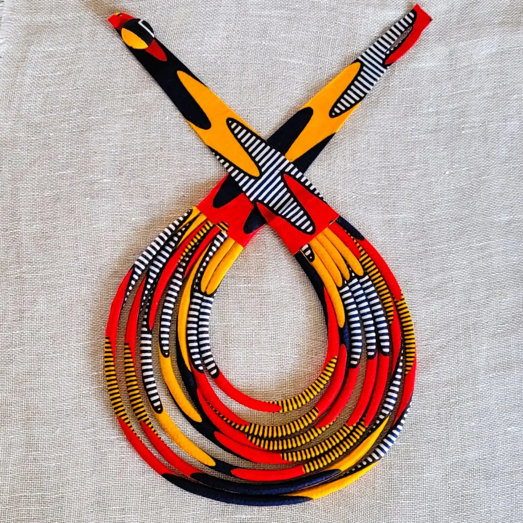 collier en tissu Nabou, un bijou africain traditionnel en pagne rouge, orange, marine et noir
