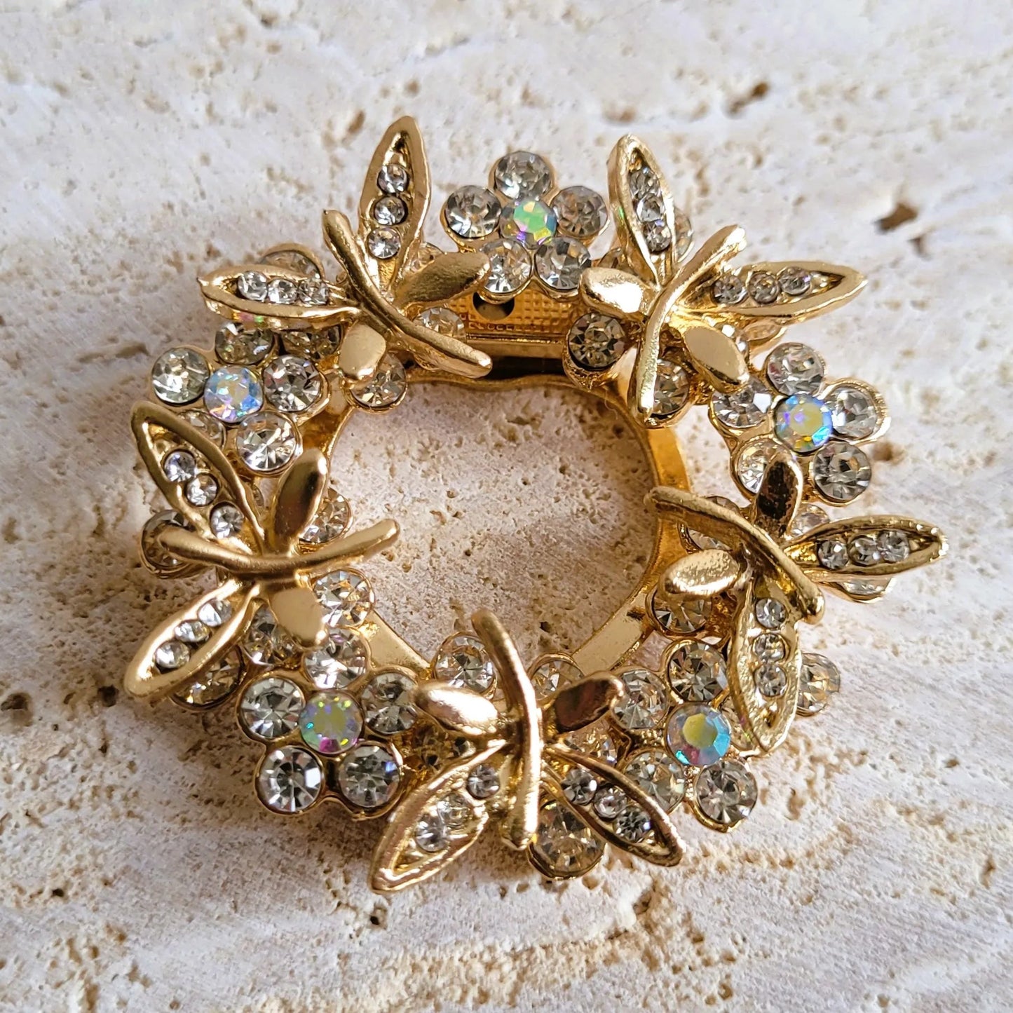 une broche dorée Aurélis en couronne de strass et papillons pour sublimer un petit haut