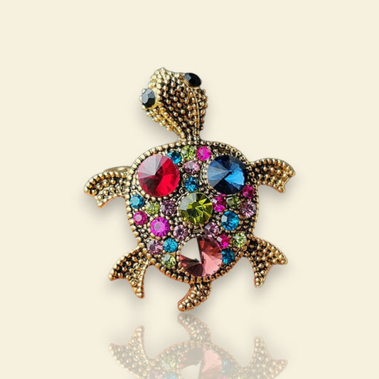 broche dorée Caroline, une broche d’une tortue ornée de strass multicolores et de picots pour vêtement de femme