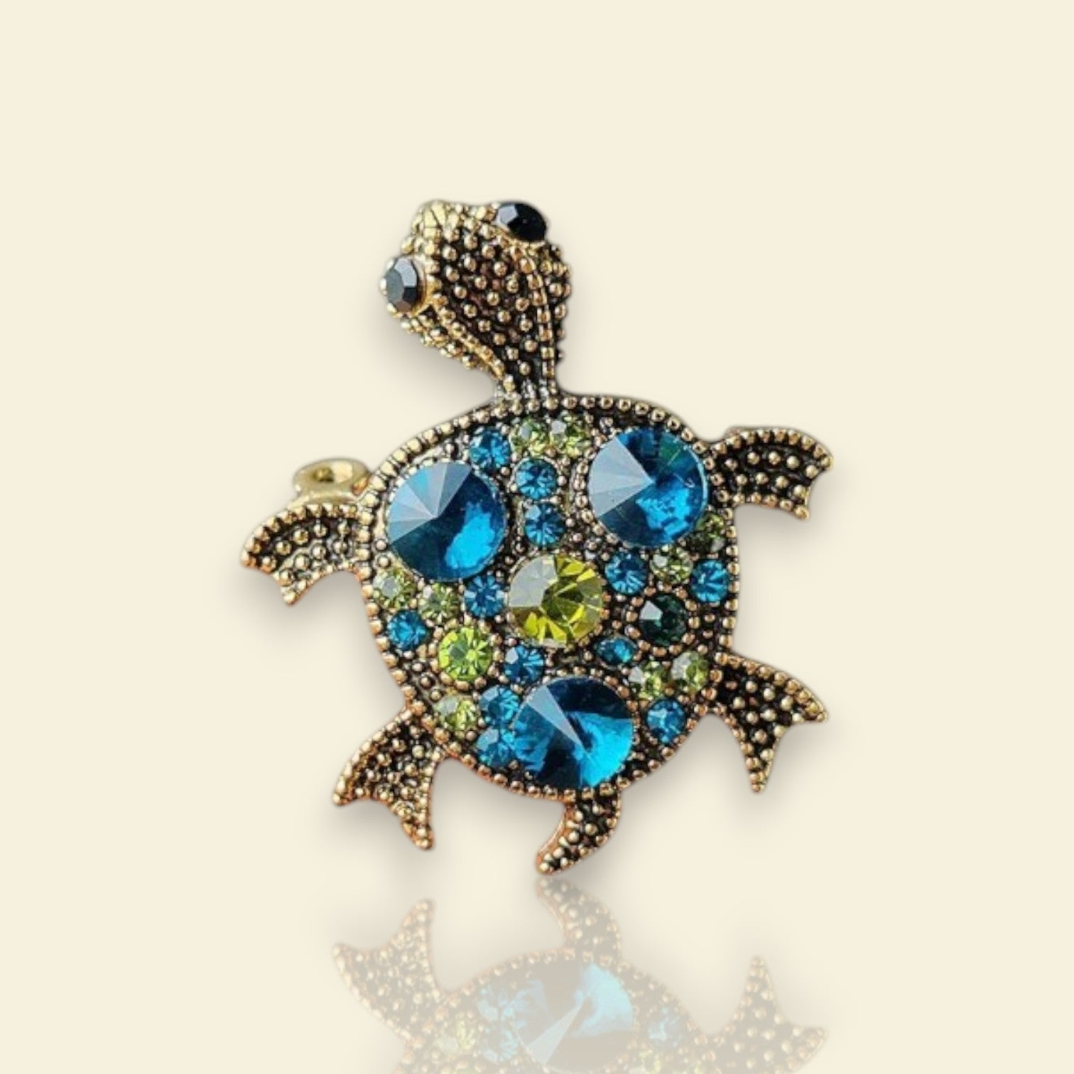 broche dorée Caroline, une broche d’une tortue ornée de strass bleus et de picots pour vêtement de femme