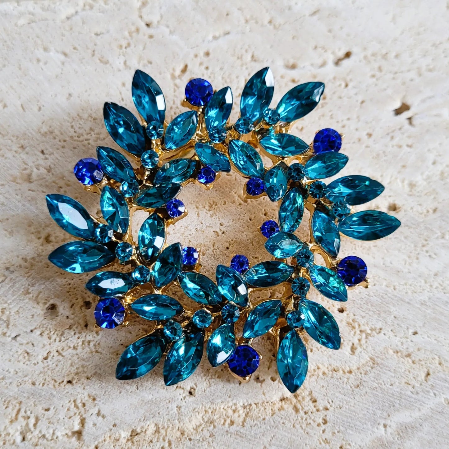 broche dorée Merveilleuse, une broche en forme de couronne de strass bleue pour vêtement de femme