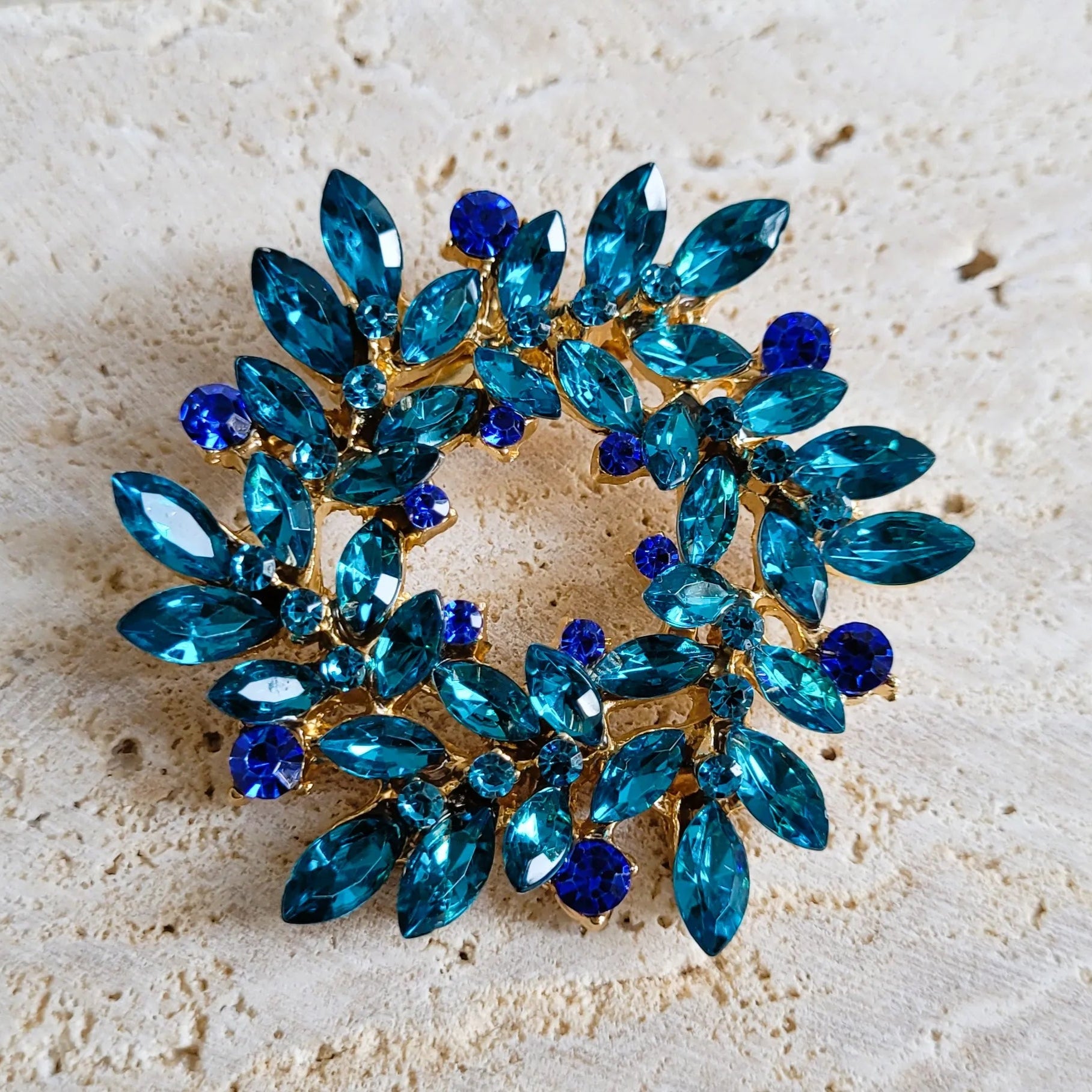 broche dorée Merveilleuse, une broche en forme de couronne de strass bleue pour vêtement de femme