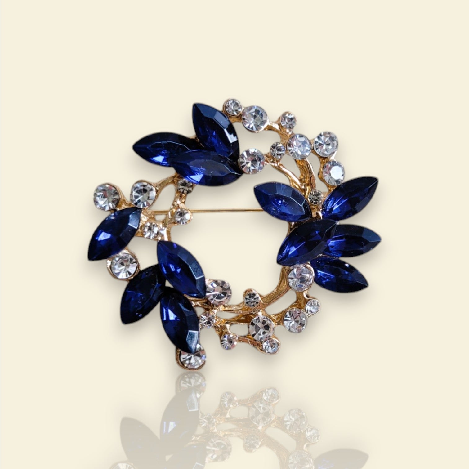 broche dorée Sublim, un bijou moderne en forme de couronne de strass bleus et cristal