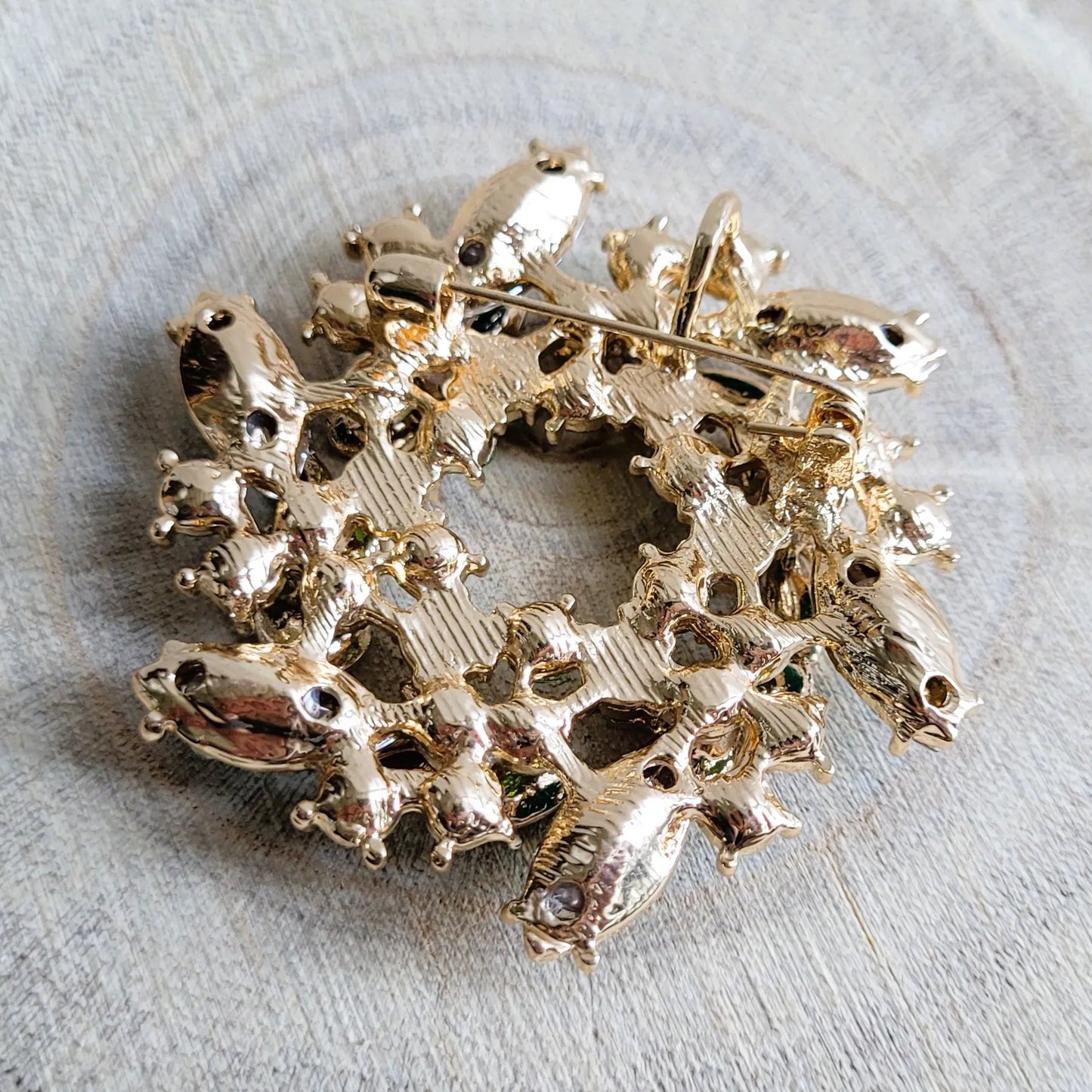 une broche dorée Végétalia en couronne de feuilles vert émeraude pour sublimer un petit haut