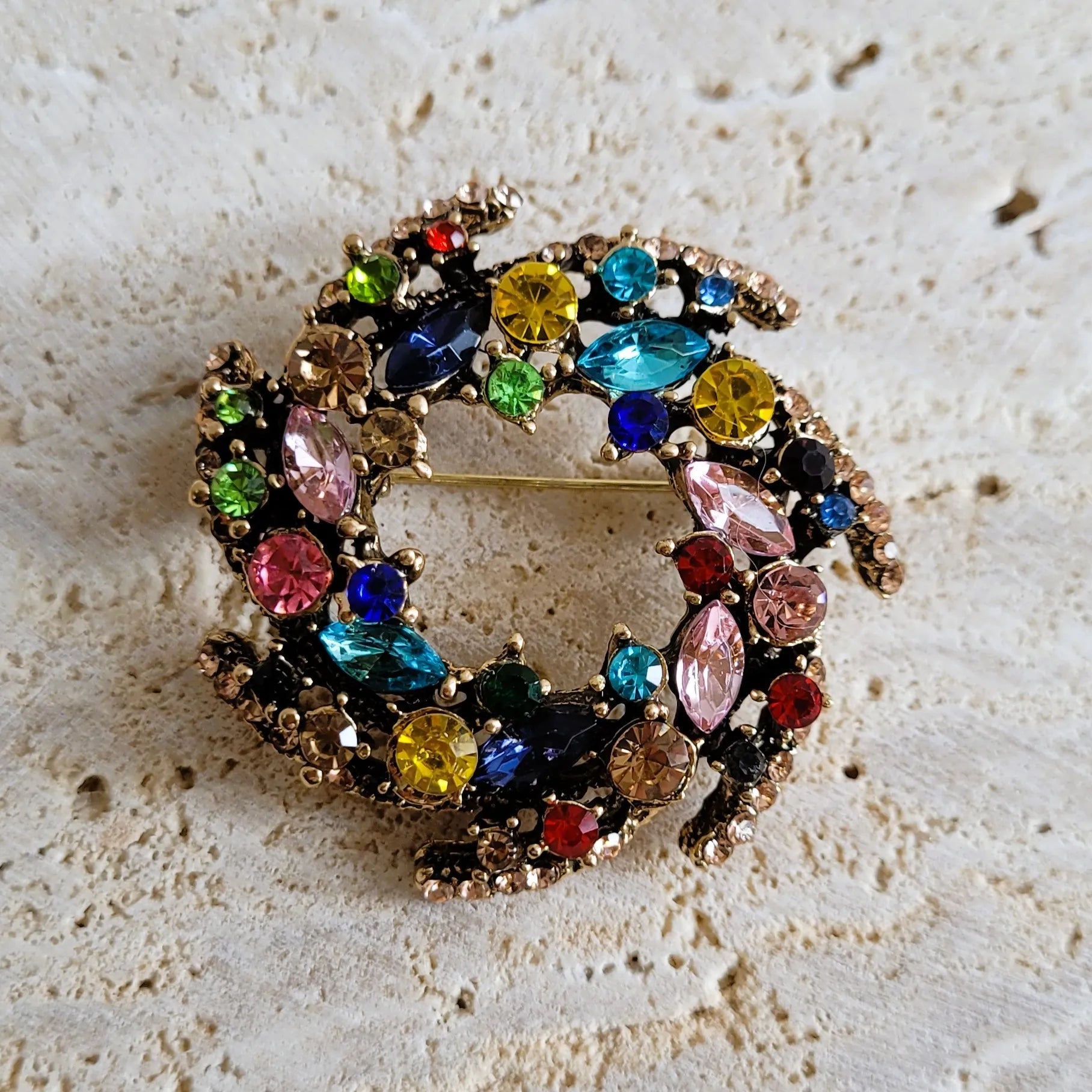 une broche dorée Vivella en couronne de strass multicolores pour sublimer un petit haut
