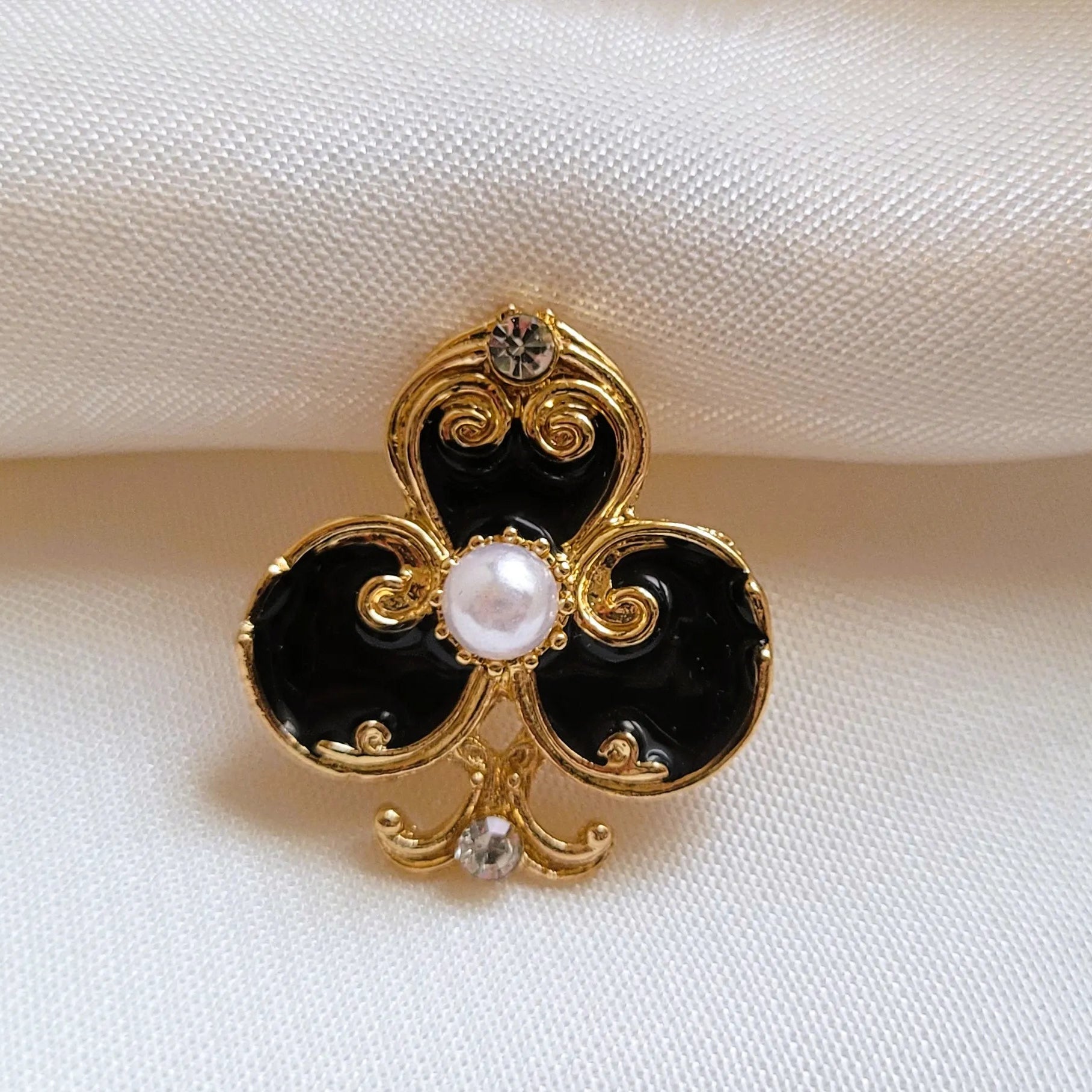 broche pour vêtement de femme Fortuna, un bijou en forme d’as de trèfle doré et noir