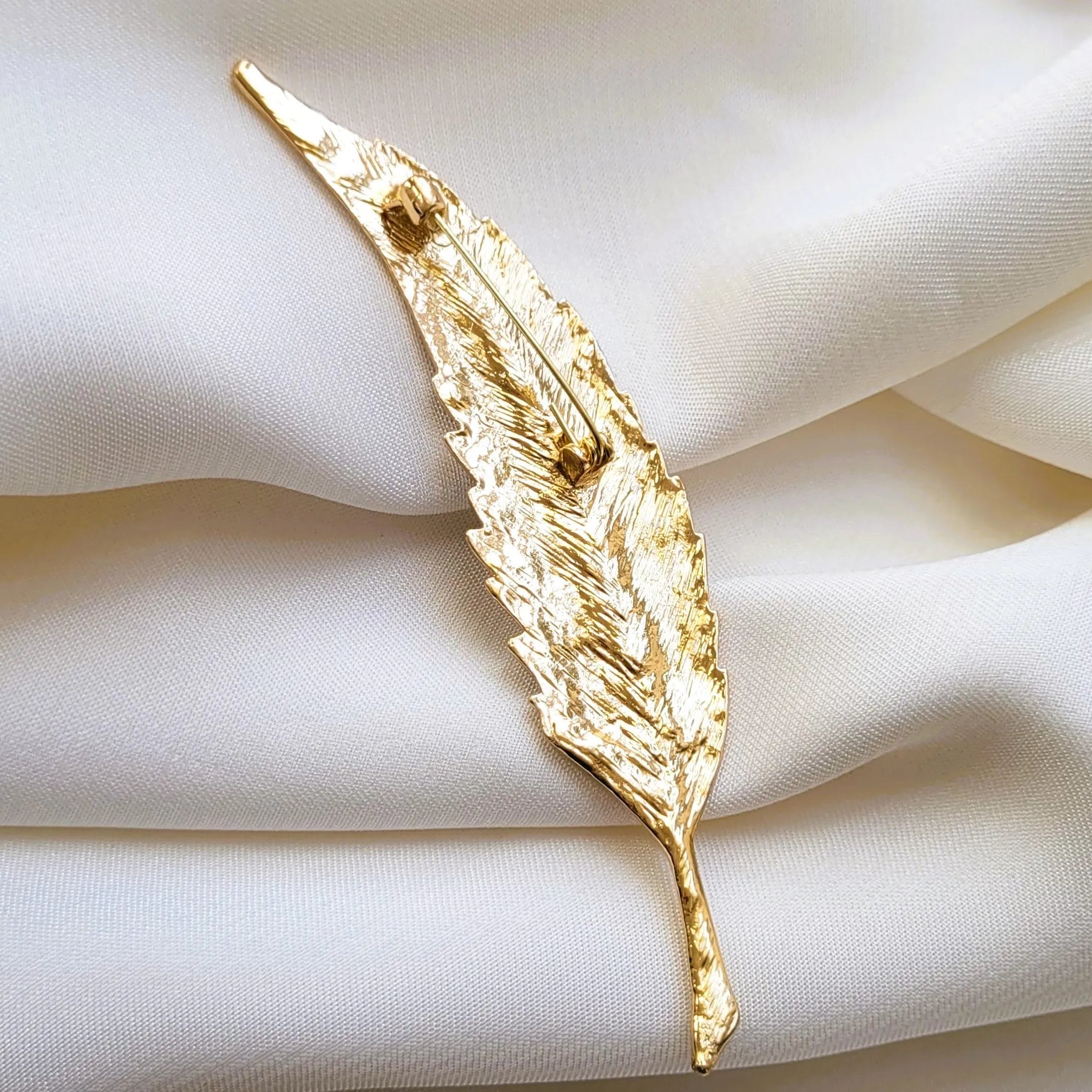 broche pour vêtement de femme Maât, un bijou moderne en forme de plume élancée