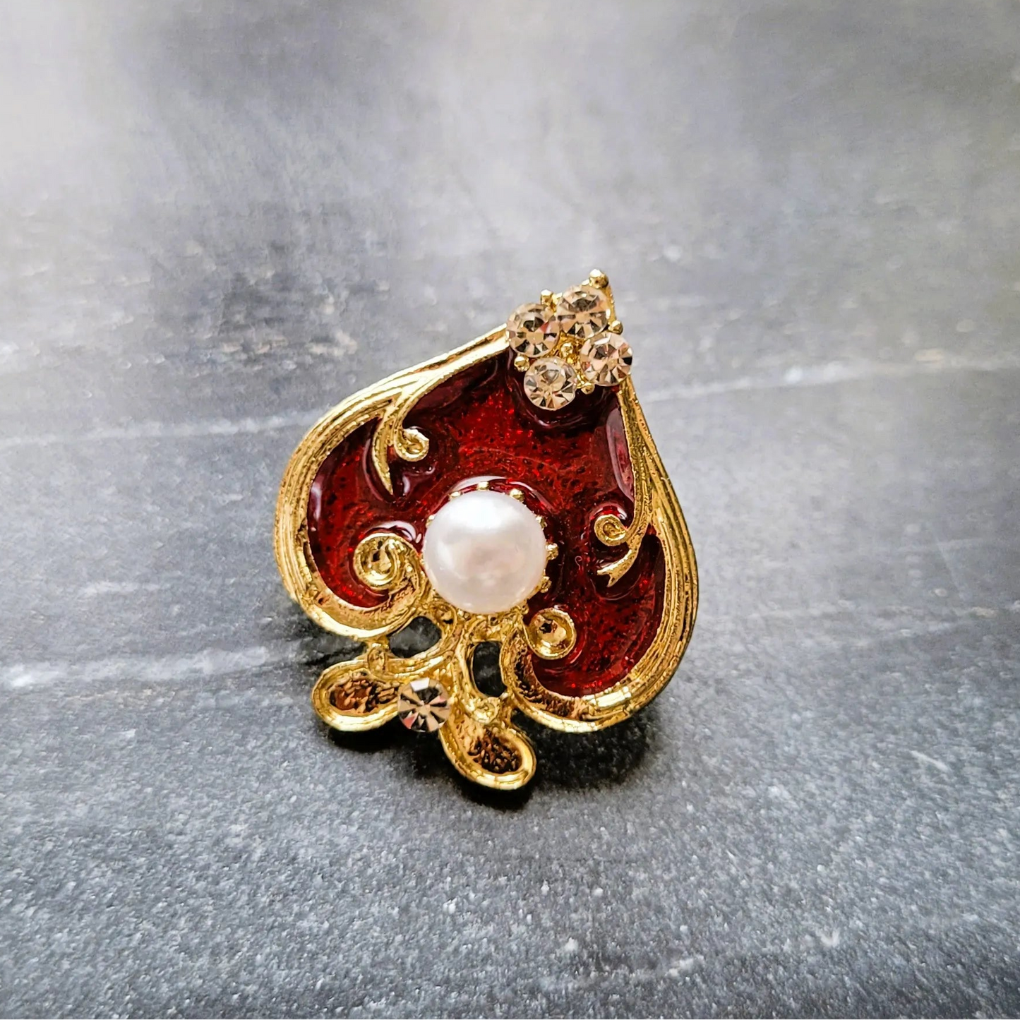 broche pour vêtement de femme Spadia, un bijou en forme d’as de pic doré et rouge