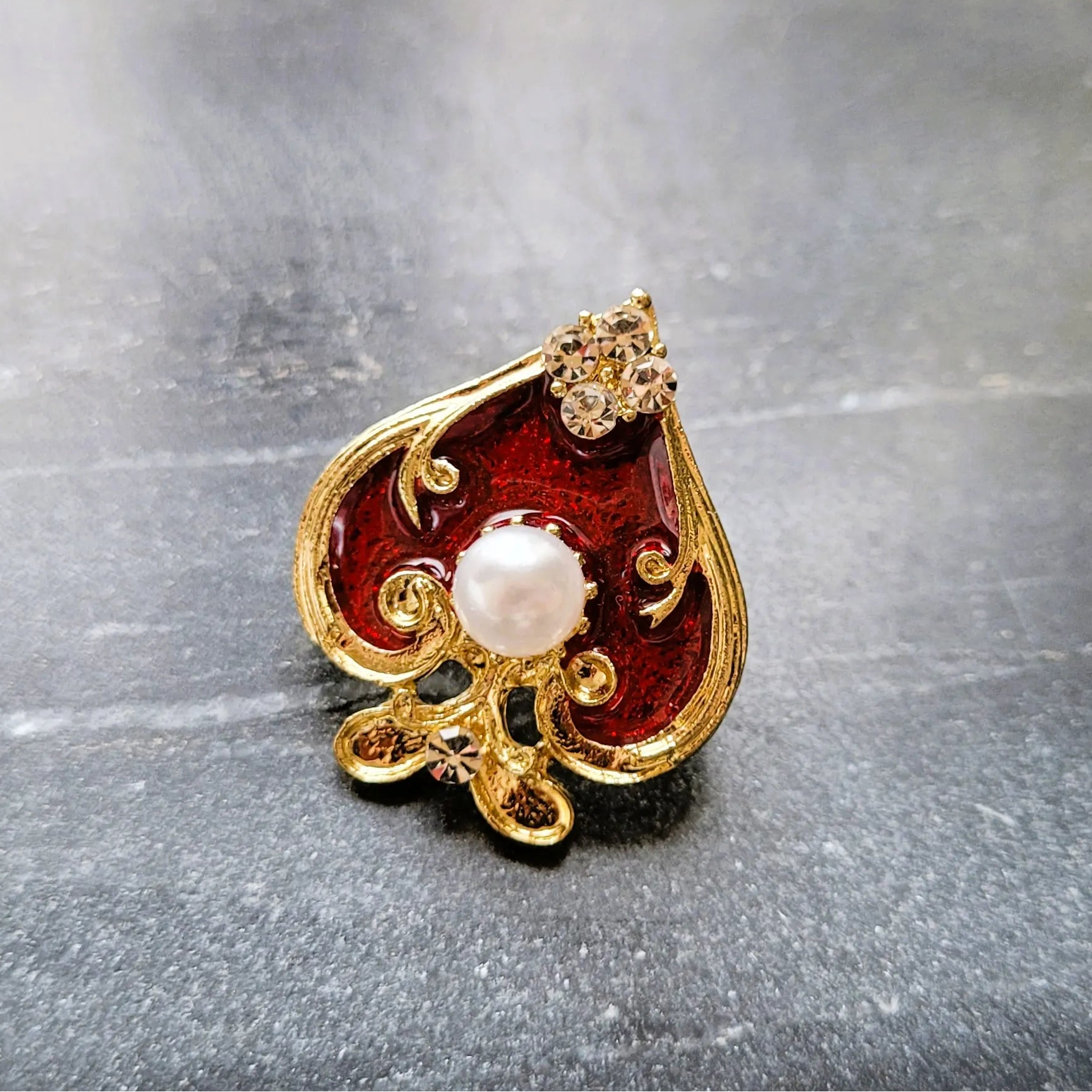 broche pour vêtement de femme Spadia, un bijou en forme d’as de pic doré et rouge