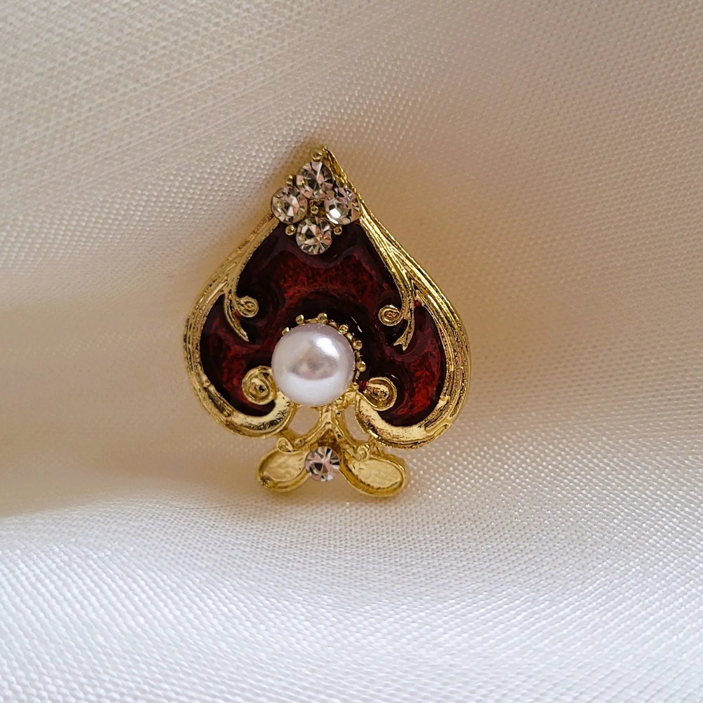 broche pour vêtement de femme Spadia, un bijou en forme d’as de pic doré et rouge