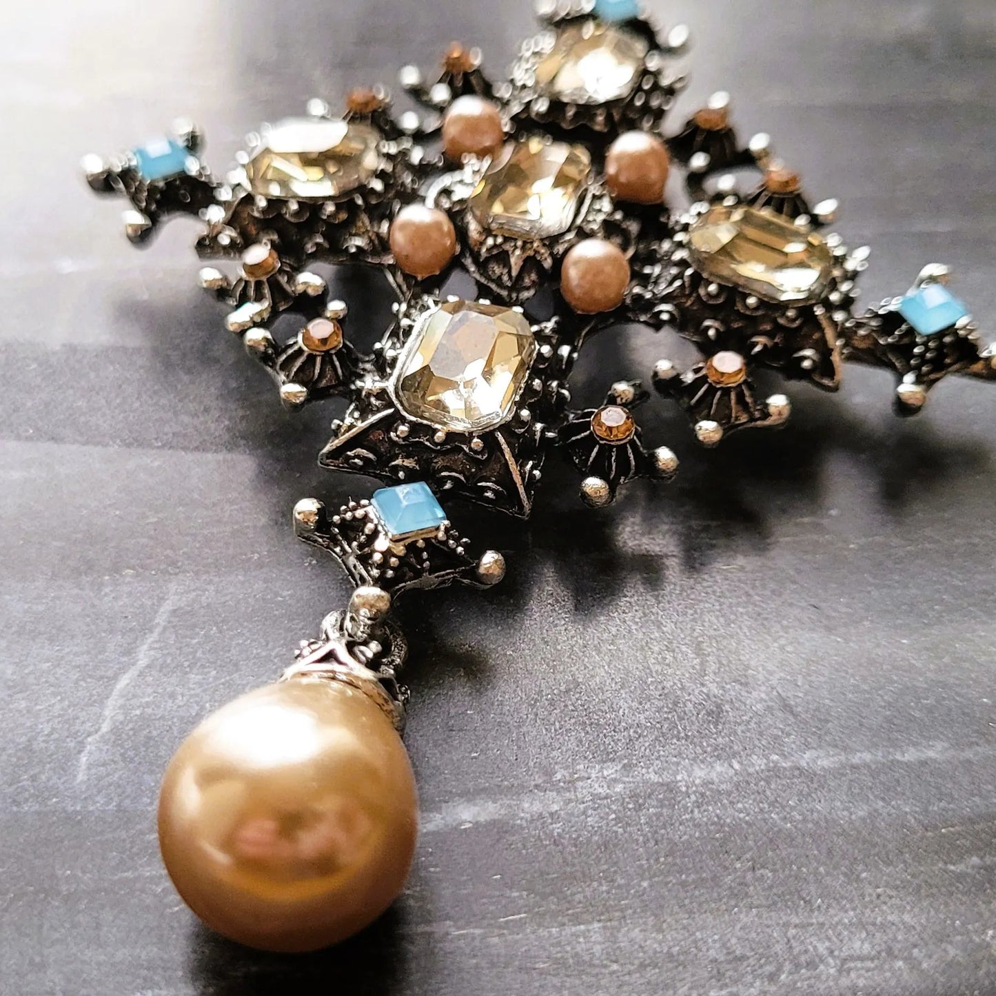 broche pour vêtement de femme Trinité, une broche fantaisie argentée, parée de strass et d’une perle goutte