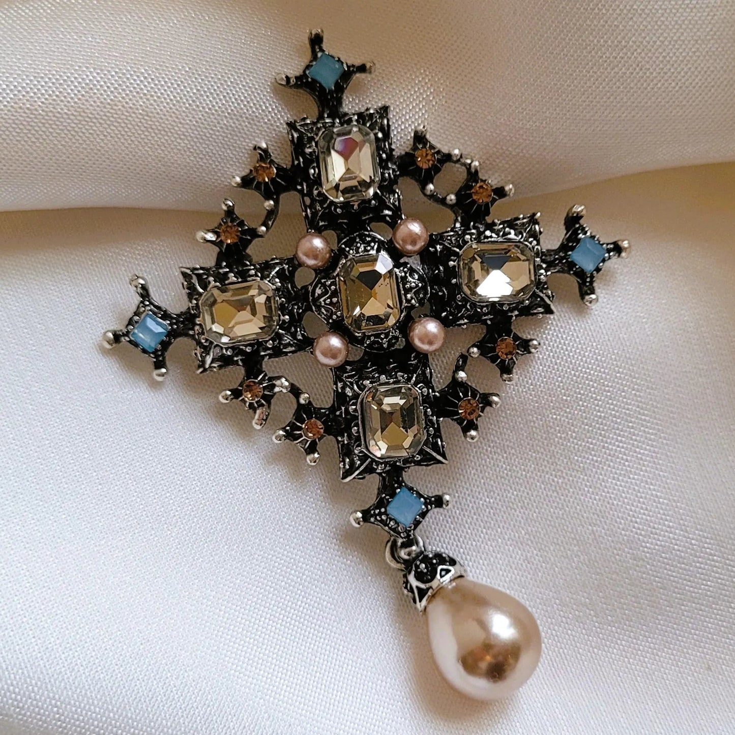 broche pour vêtement de femme Trinité, un bijou argenté paré de strass et d’une perle goutte
