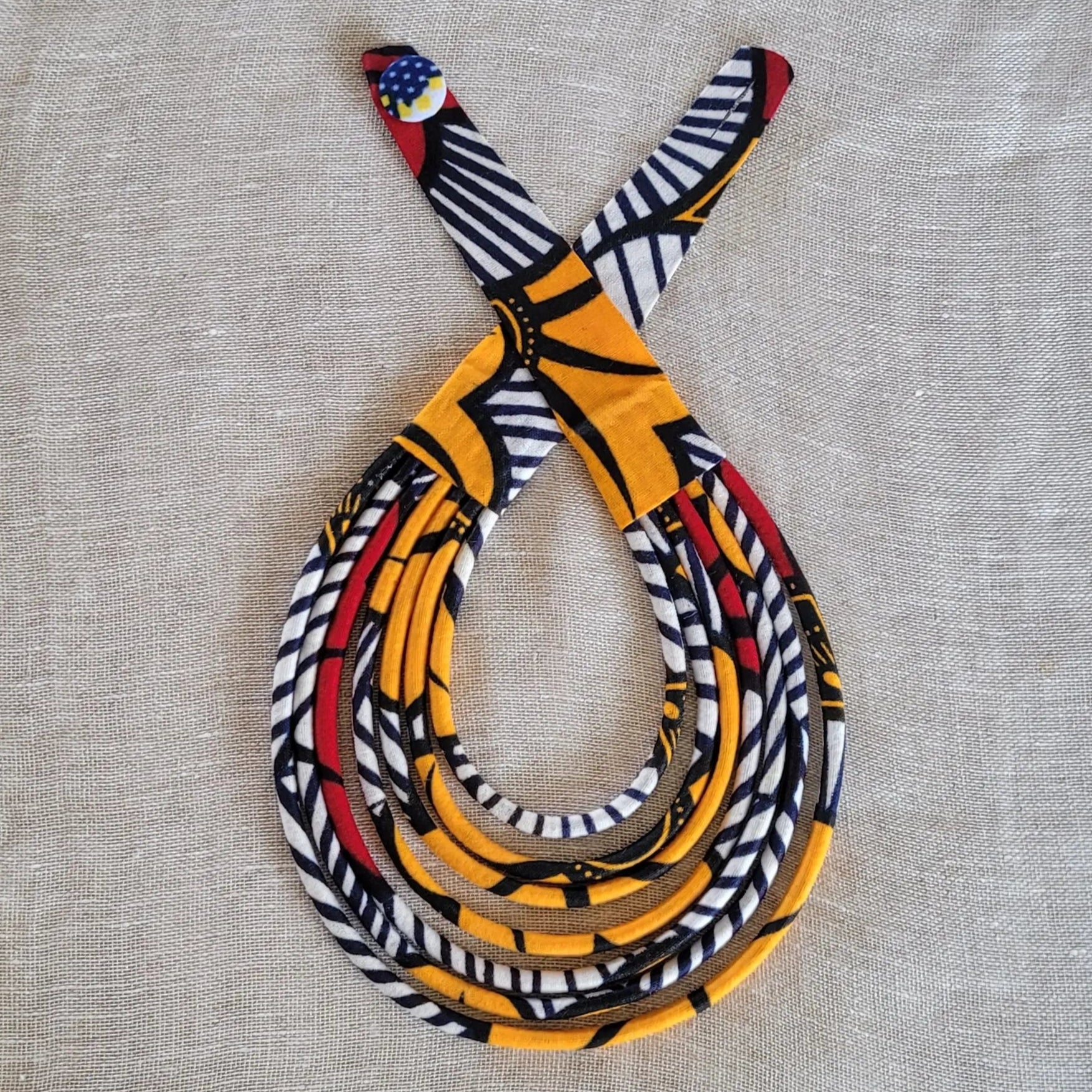 collier en tissu Ndidé, un bijou africain traditionnel en pagne orange et blanc