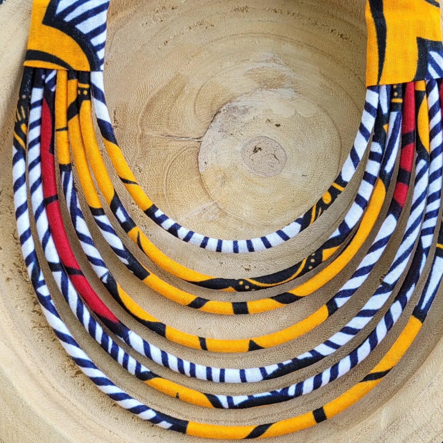 collier en tissu Ndidé, un collier coloré composé de sept rangs de cordons recouverts de tissu wax