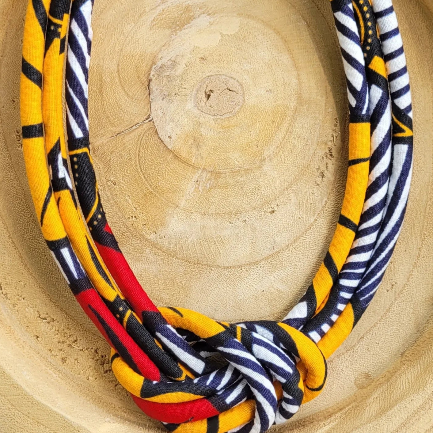 collier en tissu Rokhaya, un collier coloré composé de trois rangs de cordons recouverts de tissu wax entrelacés